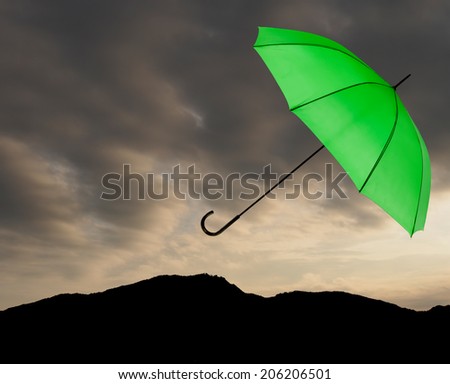 Bad weather background. Green umbrella over stormy sky. Landscape silhouette.
