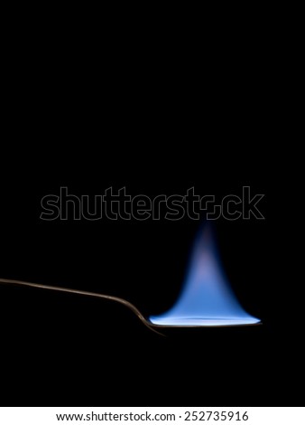 Real flame on spoon. Fire, light background or food danger concept.