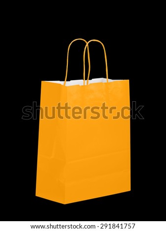 Orange colour paper carrier bag, isolated on black. Halloween shopping maybe.