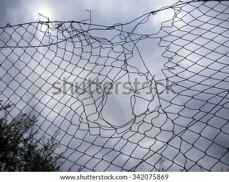 Hole in the fence. Mesh wire boundary.