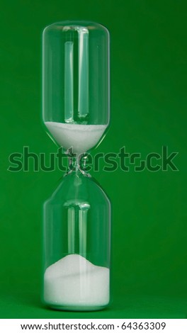 Simple glass eggtimer with time running out, over green