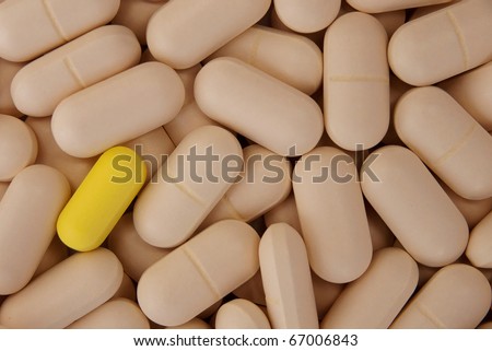A yellow pill standing out from the rest -medical breakthrough concept