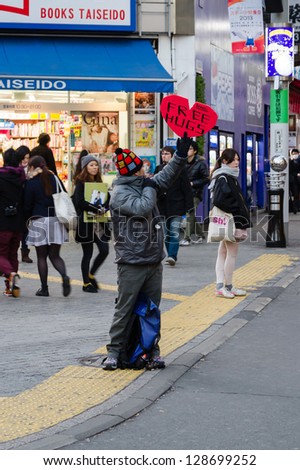 TOKYO, -Â?Â? JANUARY 17: A young man with a \'Free Hugs\' sign embraces a stranger on January 17, 2013 in Tokyo, Japan.