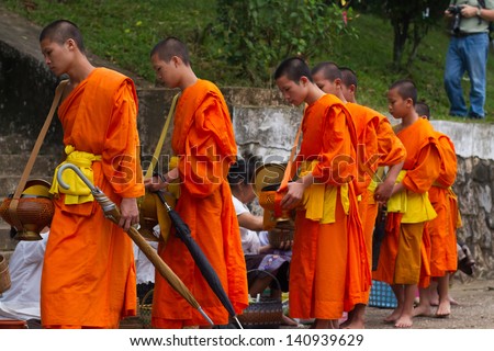 LUANG PRABANG, LAOS - SEPTEMBER15; Unidentified monks walk to collect alms and offerings on September 15, 2012 Laos. This procession is held every day in Luang prabang in the early morning