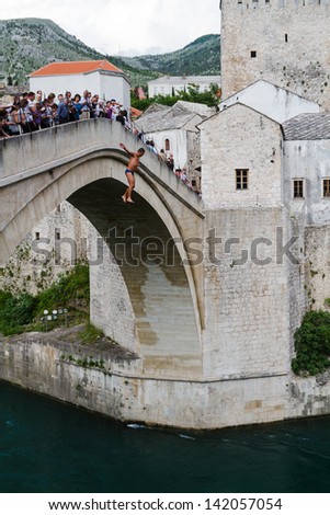 MOSTAR, BOSNIA- MAY 13: Man jumping from old bridge on MAY 13, 2013 in Mostar, Bosnia. It is a tradition for men to dive off the 21m bridge to impress visitors and earn some extra money.
