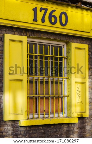 Beautiful yellow window with bars and shutter on the brick wall