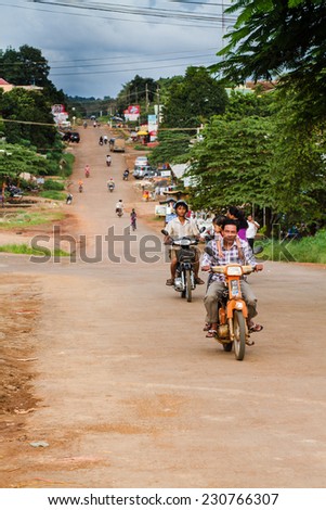 RATANAKIRI, CAMBODIA - SEP 20: People drive down the street in Ratanakiri, Cambodia on Sep 20, 2011. Scooters are very popular means of transportation in Cambodia.