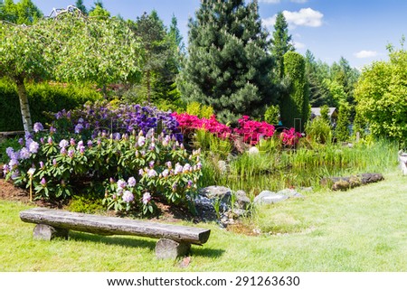 BIELSKO BIALA, POLAND - MAY 16: well kept garden with azalea and rhododendrons and old wood as table and chairs in Bielsko Biala, Poland on May 16, 2015.