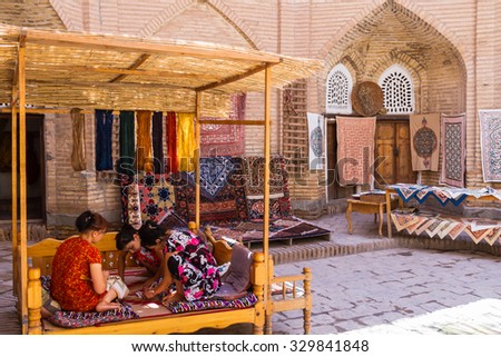KHIVA, UZBEKISTAN - MARCH 14, 2015: Unidentified female weaver knotting a handmade carpet in Khiva, Uzbekistan, Central Asia. Uzbekistan is popular with hand made carpets.