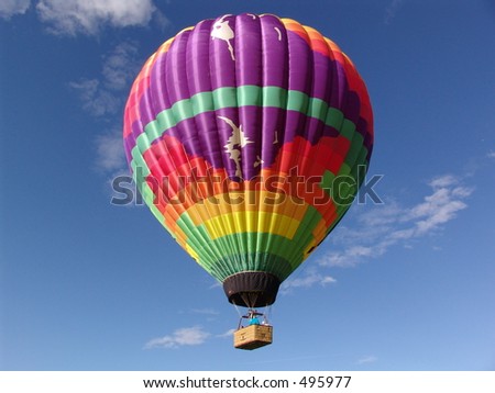 Colorful hot air balloon and basket, rising in the blue sky