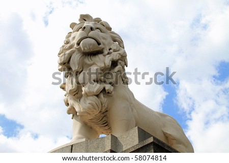 Imposing lion statue guarding the south bank of the Thames River near the London Eye ferris wheel attraction in London