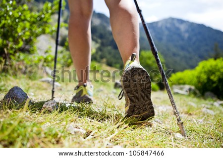 Woman Hiking In Mountains, Adventure And Exercising. Legs And Nordic Walking Poles In Summer Nature.