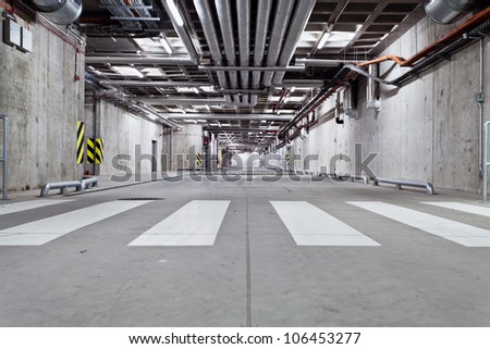 Parking garage, underground interior with zebra crossing, crosswalk, industry and technology. Neon light in bright industrial building.