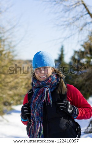 Young woman hiking in winter mountains. Sport and fitness outdoors on snow in forest, beautiful female hiker walking with backpack.