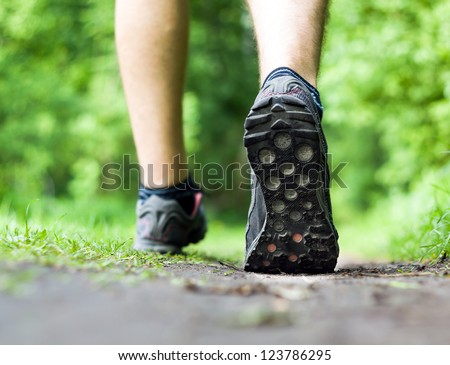 Man walking or running on trail in forest summer nature outdoors, sport shoes and exercising on footpath