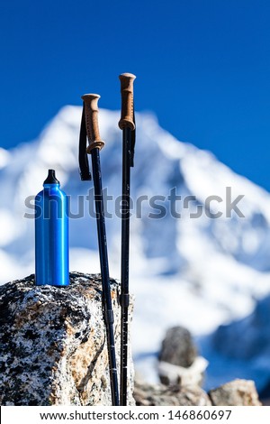 Hiking equipment in Himalaya Mountains, Nepal. Trekking pole, stick and water bottle on mountain rock outdoors in nature.