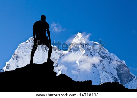 Man hiking silhouette in Himalaya mountains. Male hiker with backpack on top of mountain looking at beautiful night Mount Ama Dablam in Himalayas, Nepal