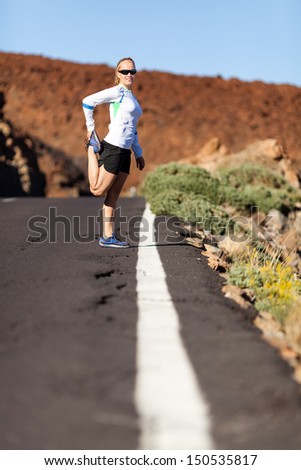 Young woman running in mountains on  sunny day. Female runner stretching and exercising outdoors in summer nature, sunset.