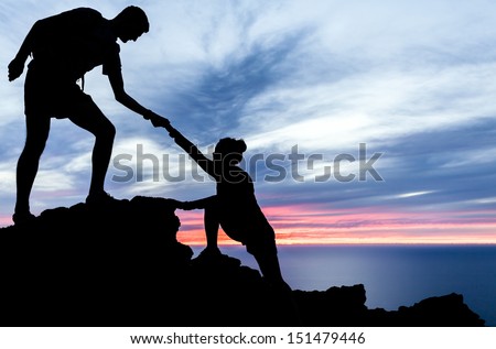 Couple Hiking Silhouette In Mountains, Sunset And Ocean. Male And Woman Hiker Helping Each Other On Top Of Mountain Looking At Beautiful Night Landscape.