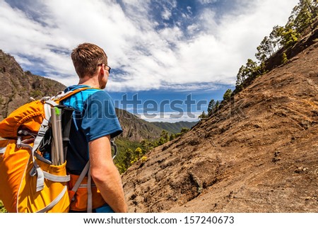 Hiking or trail running man in mountains. Backpacker looking at beautiful mountain view. Fitness and healthy lifestyle outdoors in summer nature, La Palma on Canary Islands.