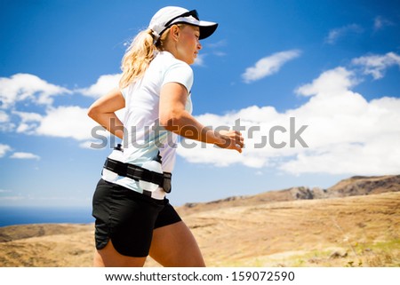 Young woman running in mountains on sunny summer day. Female runner exercising outdoors in nature, sunset, walking runner exercise in nature
