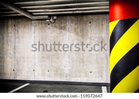 Parking garage underground interior. Concrete grunge wall and column with warning sign, industrial interior.