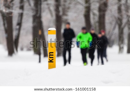 People running in park on snowy winter. Man runner jogging white snow in cold weather nature in forest.