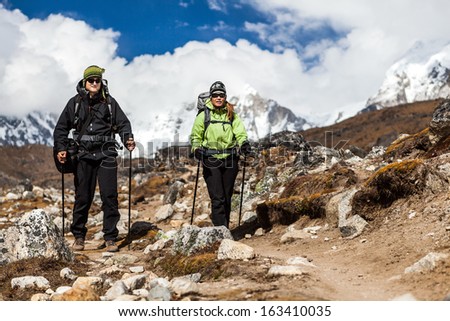 Couple hiking in himalayas mountains in Nepal. Man and woman hikers walking mountain footpath, sunny day traveling.