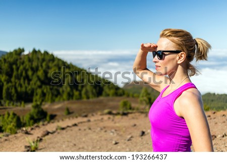 Young woman running in mountains on sunny summer day looking at view. Beauty female runner jogging and exercising outdoors in nature, rocky trail footpath on La Palma, Canary Islands