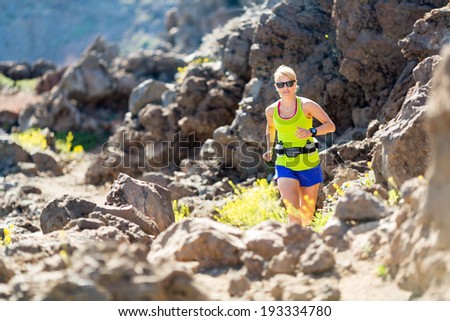 Young woman running in mountains on sunny summer day. Beauty female runner jogging and exercising outdoors in nature, rocky trail footpath on La Palma, Canary Islands