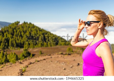 Young woman cross country running in mountains on sunny summer day. Beauty female runner jogging and exercising outdoors in nature, rocky trail footpath on La Palma, Canary Islands