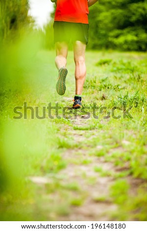 Man runner cross country running on trail in summer forest. Young athlete male training and doing workout outdoors in nature. Jogging workout fitness concept.