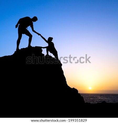 Couple hiking help each other hand teamwork partners climbing silhouette in mountains, achieve adventure. Male and woman hiker helping each other on top of mountain, beautiful sunset landscape.