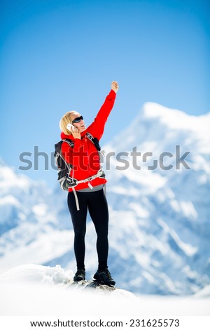 Young happy woman hiker talk on the phone on mountain peak summit in winter mountains. Climbing inspiration and motivation, beautiful landscape. Fitness healthy outdoors activity in Himalayas, Nepal