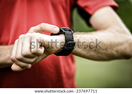 Runner on mountain trail looking at smartwatch or sport watch, checking gps navigation position map or heart rate pulse trace, using heart monitor equipment. Sport and fitness outdoors in nature.