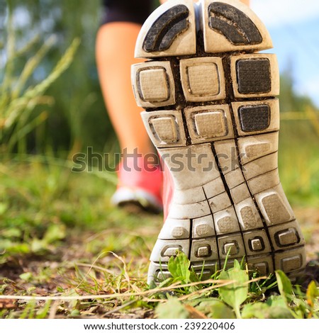 Walking or running exercise shoes close-up, legs on green grass footpath in forest, achievement fitness adventure and exercising in spring or summer nature