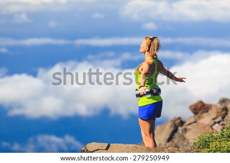 Happy woman runner joyful with arms raised outstretched smiling and ecstatic happiness with eyes closed. Fitness and exercise meditation in summer mountains nature outdoors, freedom concept.