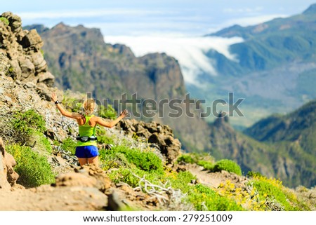 Young happy woman running or power walking in mountains on sunny summer day. Beautiful natural landscape and female runner jogging exercising outdoors in nature, rocky trail footpath on Canary Islands