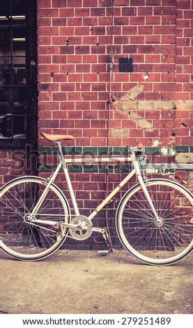 City bicycle fixed gear and red brick wall, vintage bike. Retro stylish cycling in town, old retro fix cycle, cycling or commuting in city urban environment, ecological transportation concept