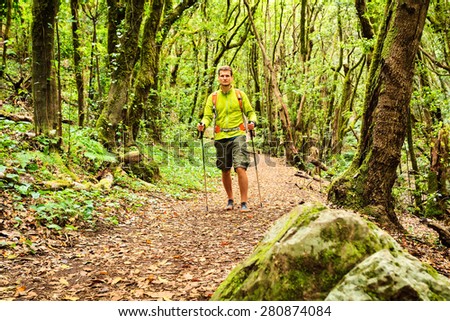 Man hiker hiking in green woods forest footpath. Young male looking around walking trip or get lost in green beautiful forest, La Gomera, Canary Islands Spain.