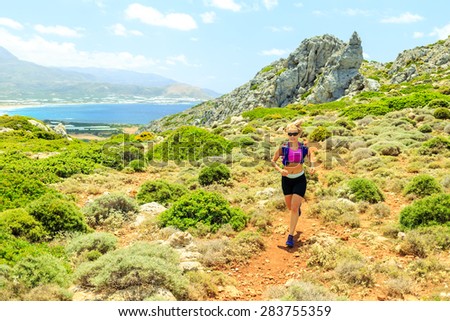 Cross country running woman trail running in inspirational mountains on summer beautiful day. Training and working out runner jogging fitness and exercising in nature, rocky footpath on Crete, Greece