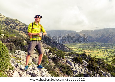 Hiking man checking direction in mountains. Hiker trekking in inspirational beautiful landscape looking at view and gps watch, sport smart watch. Healthy lifestyle outdoors concept.