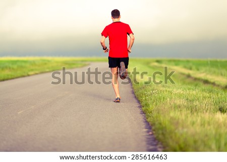 Man running on country road, healthy fitness lifestyle, sport speed training beautiful landscape. Young runner jogging training and doing workout exercising power walking outdoors in nature.