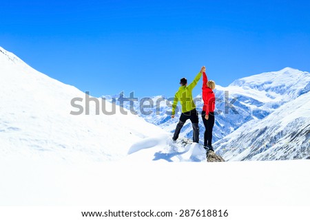 Teamwork motivation, couple hikers climbers with arms up, fitness and sport woman success in winter mountains. Inspiration beautiful landscape and healthy lifestyle on snow in Himalayas, Nepal.