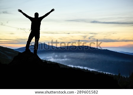 Success and achievement, hiking man silhouette concept with climber with arms up, outstretched on mountains peak, healthy lifestyle at sunset