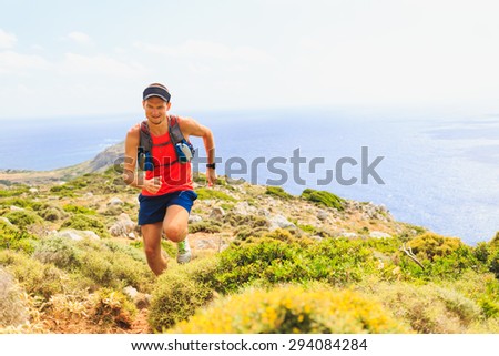 Trail running man cross country running in mountains on summer beautiful day. Training and working out runner jogging and exercising outdoors in nature, rocky footpath on Crete, Greece
