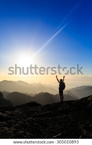 Woman successful climbing silhouette in mountains, motivation and inspiration in beautiful sunset and ocean. Hiker with arms up outstretched on mountain top, beautiful sunset inspirational landscape.