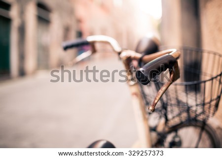 City old bicycle handlebar and basket over blurred beautiful bokeh background on Europe city street. Vintage retro style bike with bokeh copy space. Selective focus on handlebar.