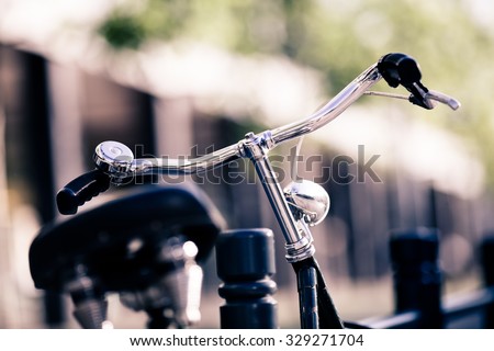 Vintage city bike colorful retro light and handlebar on street, alternative ecology transportation, commute on classic bicycle in urban scene, blurred bokeh background. Selective focus on handlebar.