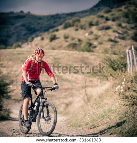 Mountain biker riding on bike singletrack trail in autumn mountains. Man rider cycling MTB on country road or single track. Sport fitness motivation, inspiration in beautiful inspirational landscape.